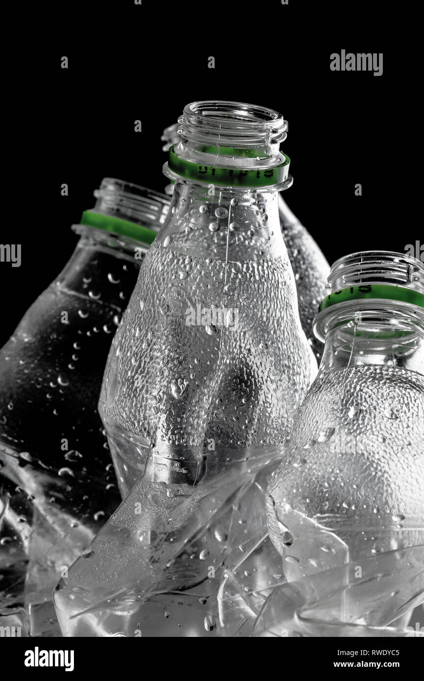 Gruppe von leeren Plastikflaschen mit grünen Caps zerschlagen, auf schwarzem Hintergrund Stockfoto