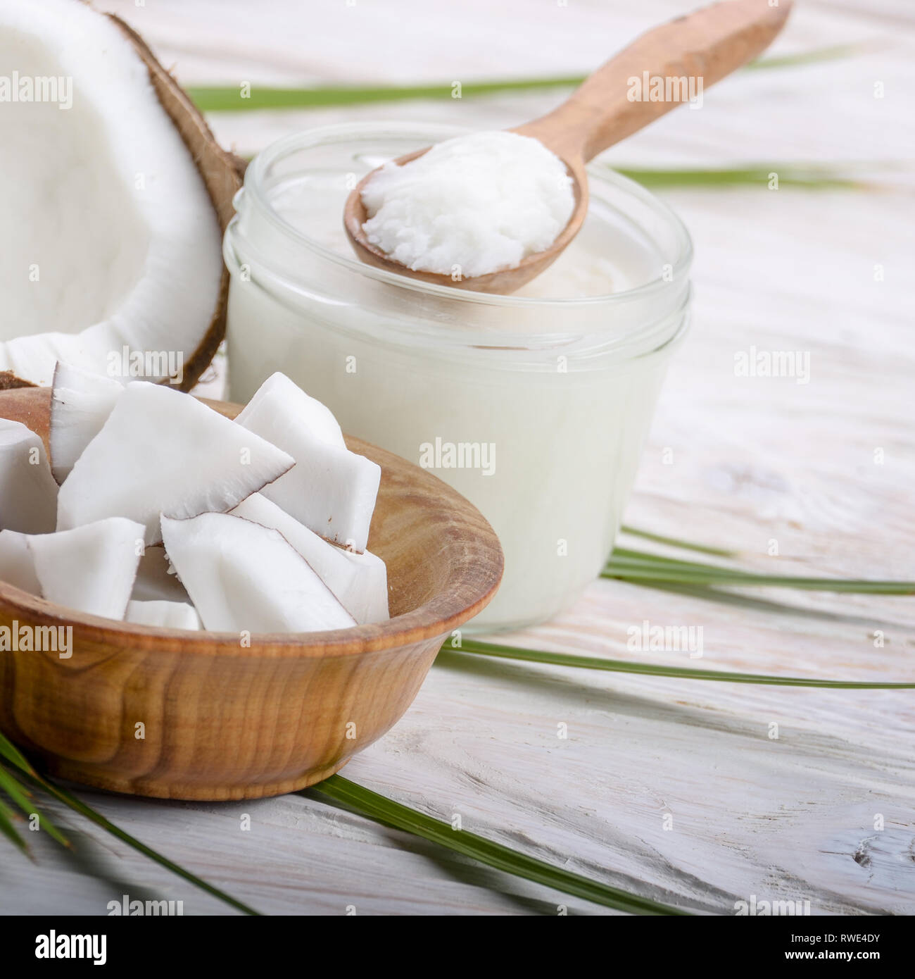 Coconut shell Schwer öl in Glas und Kokosnuss Fleischstücke in Schüssel auf weiße Holztisch Stockfoto