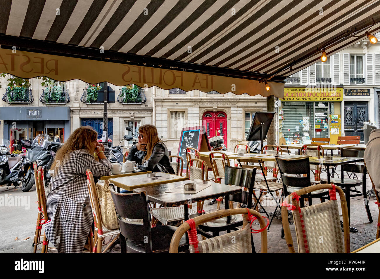 Zwei Frauen sitzen draußen an einem Tisch in einem Pariser Restaurant in St. Georges im 9. Arrondissement von Paris, Frankreich Stockfoto