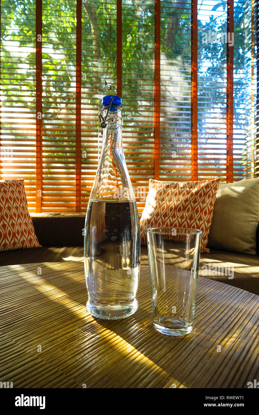 Elegante Glas Wasser Flasche auf Resort Zimmer Tabelle, mit natürlicher Beleuchtung und couch Polster, Panglao - Bohol, Philippinen Stockfoto