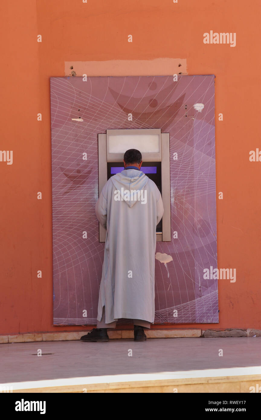 Mann in traditioneller Kleidung bei einer Bank Maschine, Medina, Marrakesch, Marokko Stockfoto