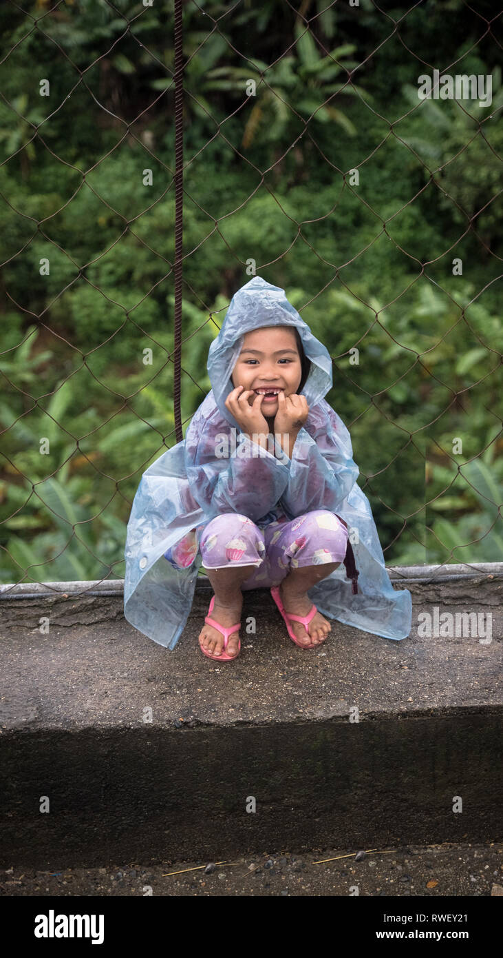 Lächelnd wenig philippinischen Mädchen im Regenmantel - Banaue, Ifugao, Philippinen Stockfoto