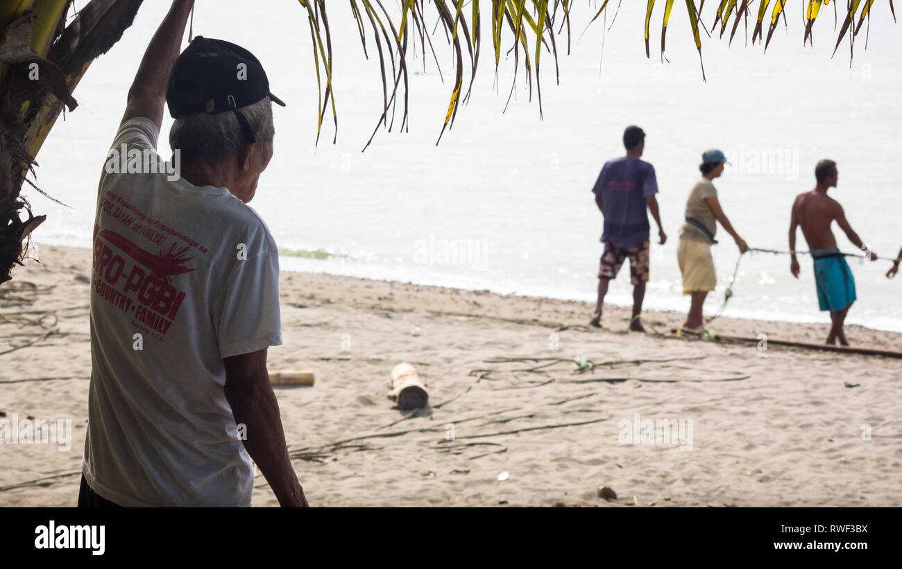 Alten Fischer beobachten, jüngere Generation ziehen Net zum Strand vom Meer - Antike, Philippinen Stockfoto