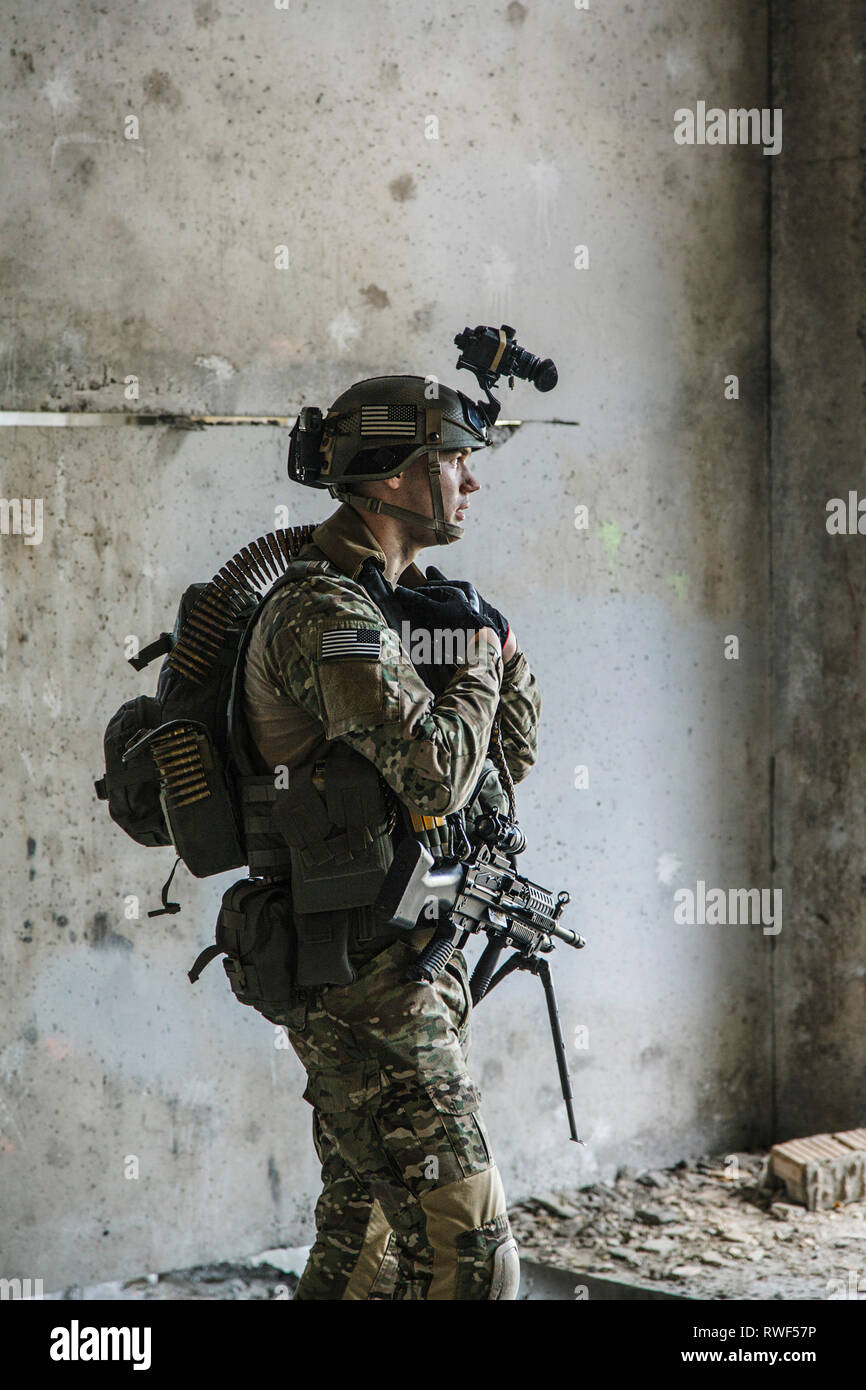 U.S. Army Ranger mit Maschinengewehr und Nachtsichtgerät steht in der Nähe der Wand. Stockfoto