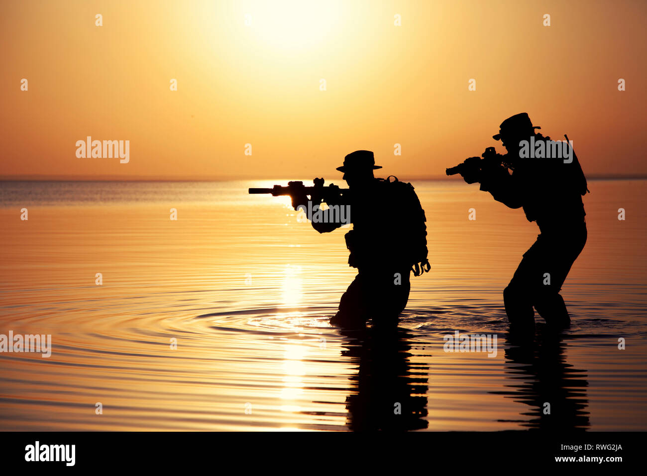Silhouette von Soldaten, die einen Fluß überquert, bei Sonnenuntergang. Stockfoto