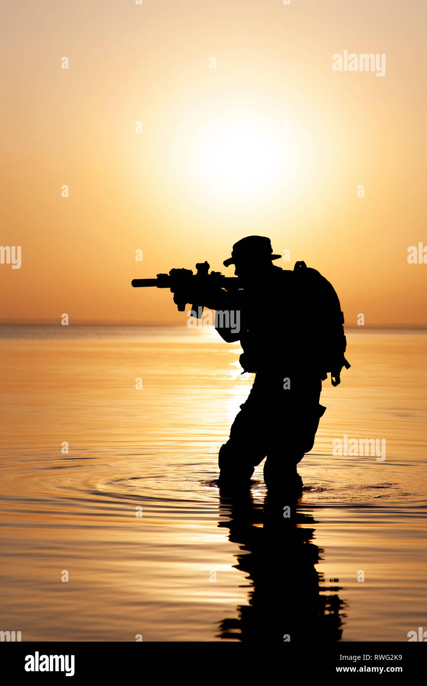Silhouette der Armee Soldat mit Gewehr gegen eine orange Sonnenuntergang. Stockfoto