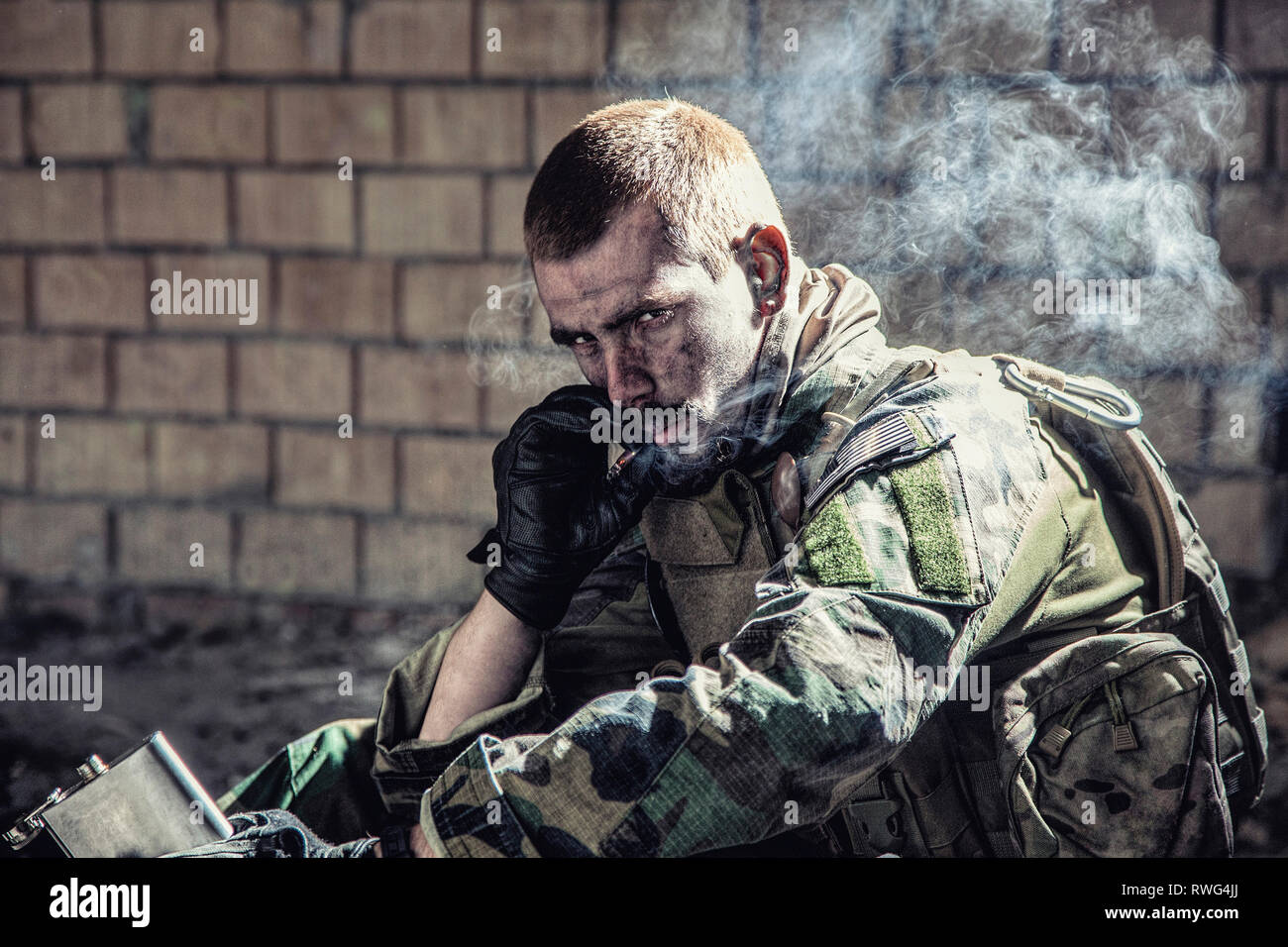 Special forces Soldaten das Rauchen einer Zigarette, während sie sich in einer Ruine sitzen. Stockfoto