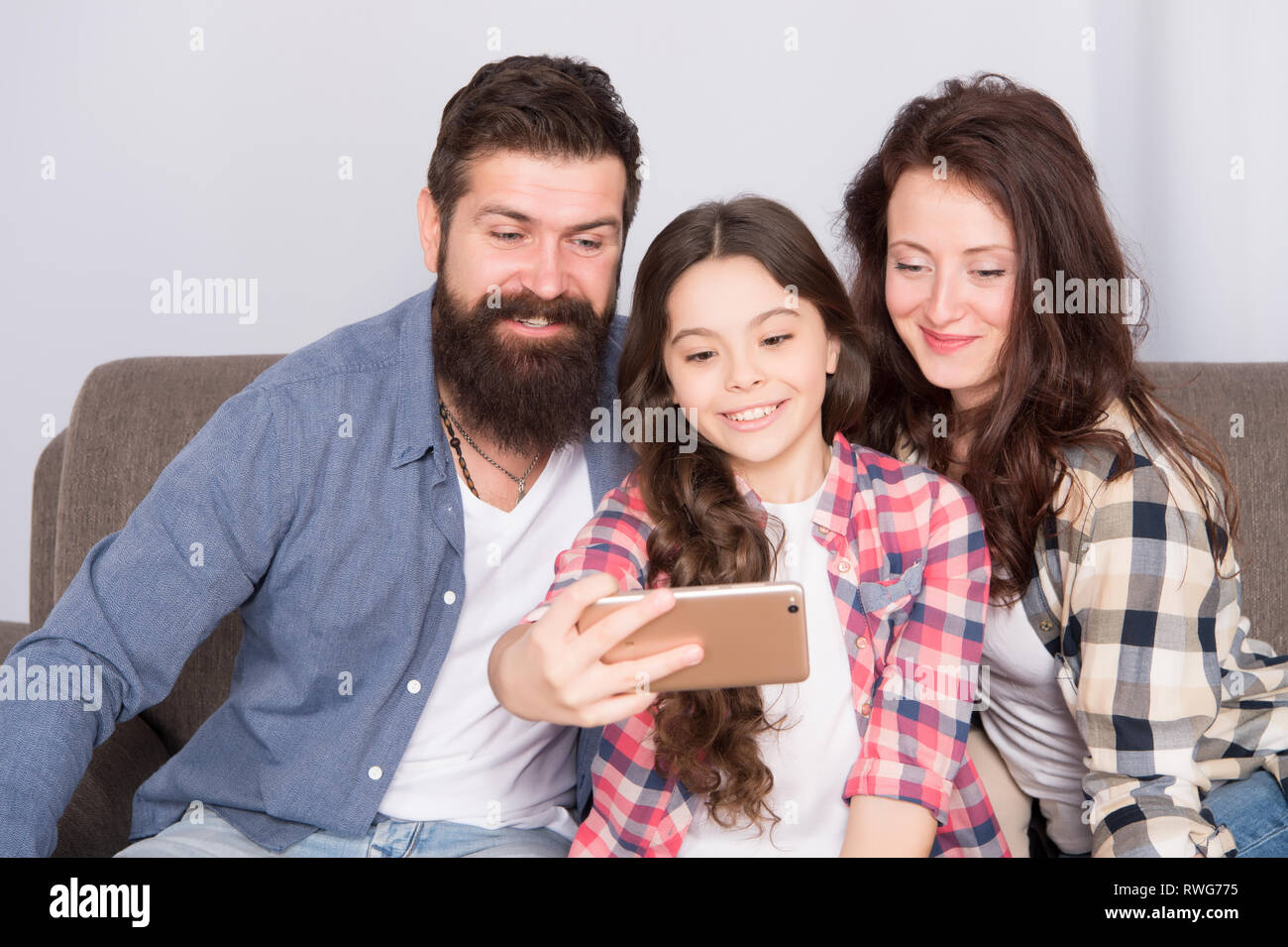 Familie selfie. Familie verbringen Wochenende zusammen. Verwendung des Smartphones für selfie. Freundliche Familie gemeinsam Spaß zu haben. Mama, Papa und Tochter entspannt auf einer Couch. Familie posieren für Fotos. Glückliche Momente festzuhalten. Stockfoto