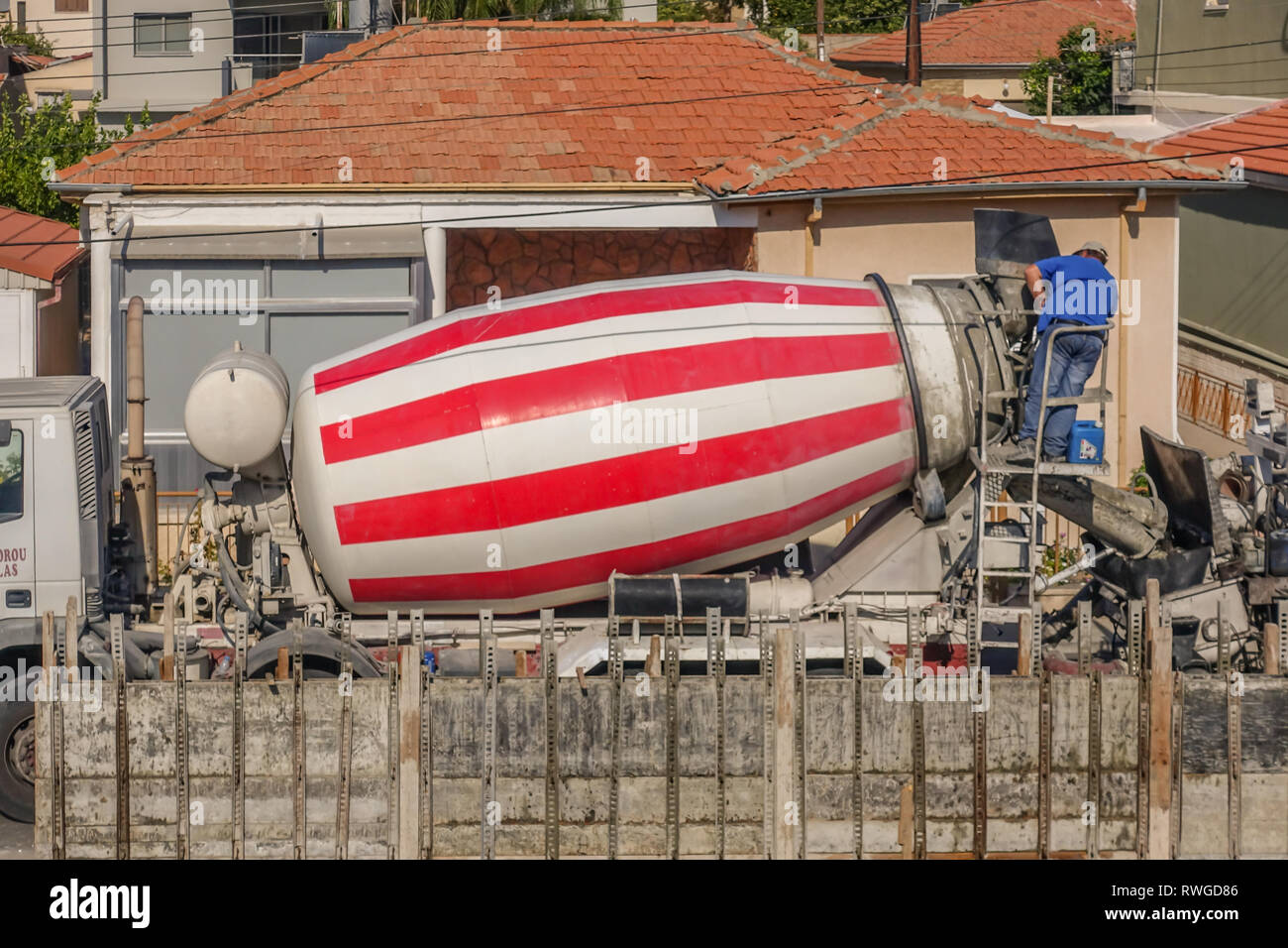 Limassol, Zypern - 3. April 2018: Rot-weiß gestreiften Betonmischer LKW mit einem Mann an der Rückseite arbeiten Stockfoto