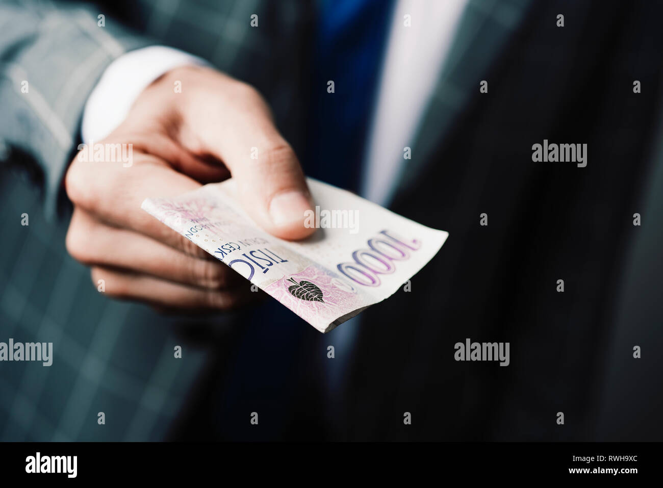 Nahaufnahme eines jungen kaukasischen Geschäftsmann, tragen einen eleganten grauen Anzug, eine 1000 Tschechische Kronen Banknote der Beobachter Stockfoto