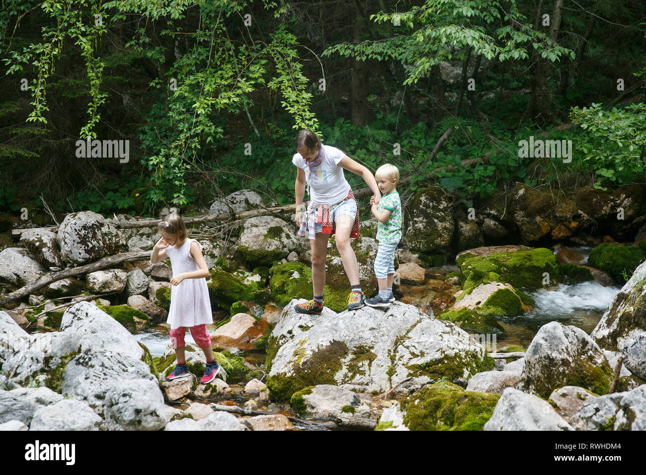 Mutter mit Kindern Spaß haben, spielen von einem Mountain Creek im Sommer. Natürliche Lebensweise, positive Parenting, Kindheit Erfahrungen Konzept. Stockfoto