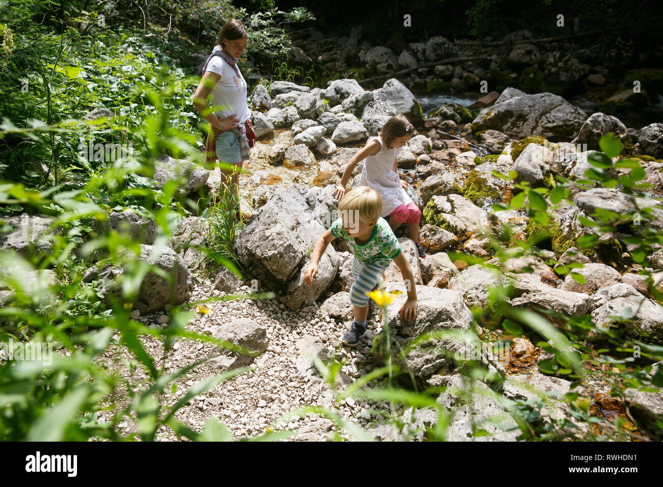 Mutter mit Kindern Spaß haben, spielen von einem Mountain Creek im Sommer. Lebensstil im Freien, positive Parenting, Kindheit Erfahrungen Konzept. Stockfoto