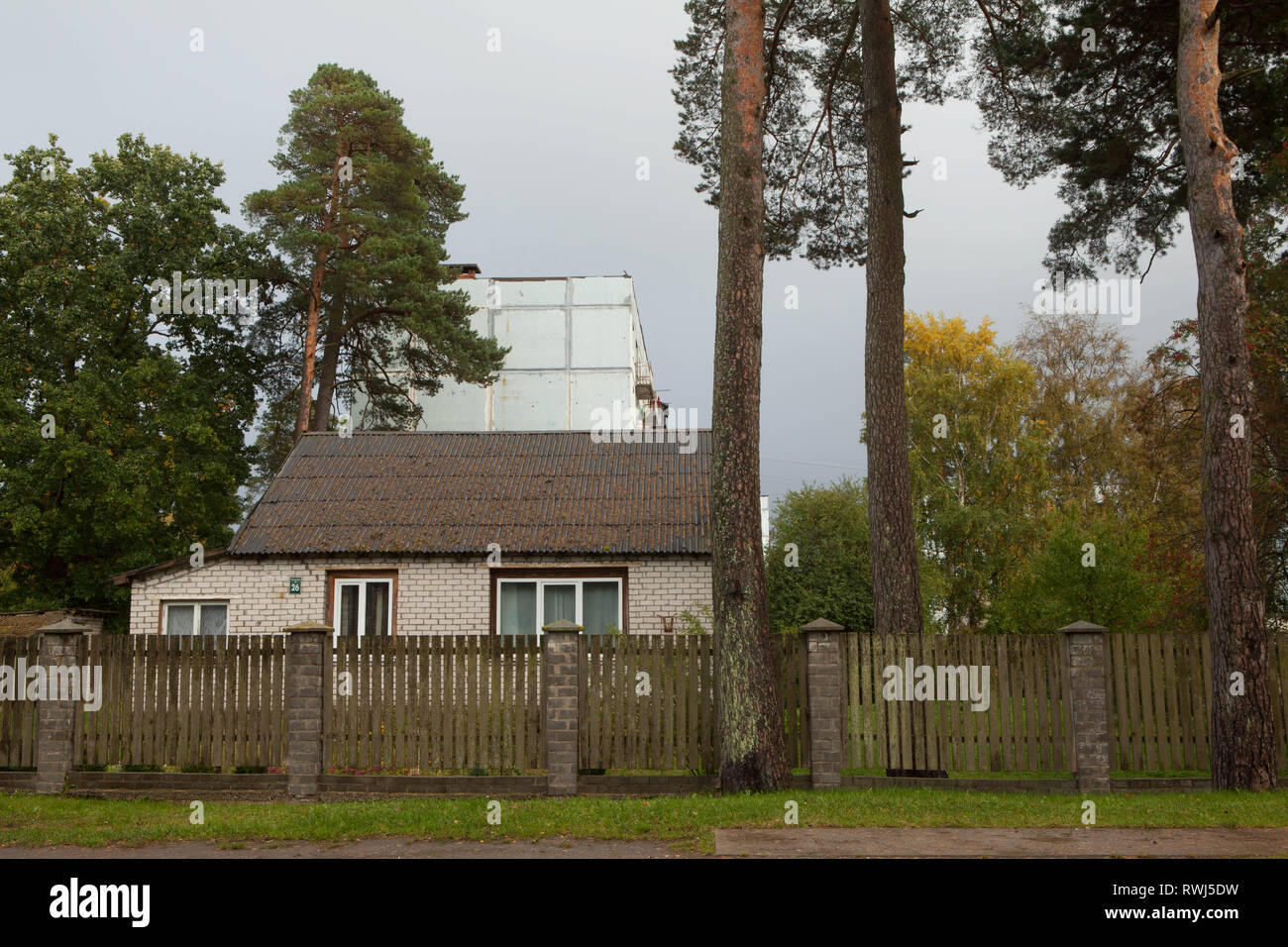 Traditionelles Haus vor der abgebrochenen Apartment Block an der ehemaligen sowjetischen Militärbasis in der Stadt von Karosta, Lettland Stockfoto