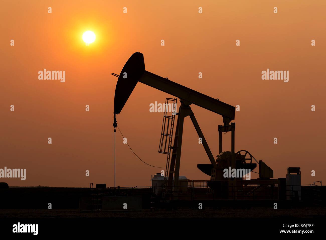 Silhouette von pumpjack mit einem leuchtenden warmen Sonne Ball im Hintergrund, westlich von Airdrie; Alberta, Kanada Stockfoto