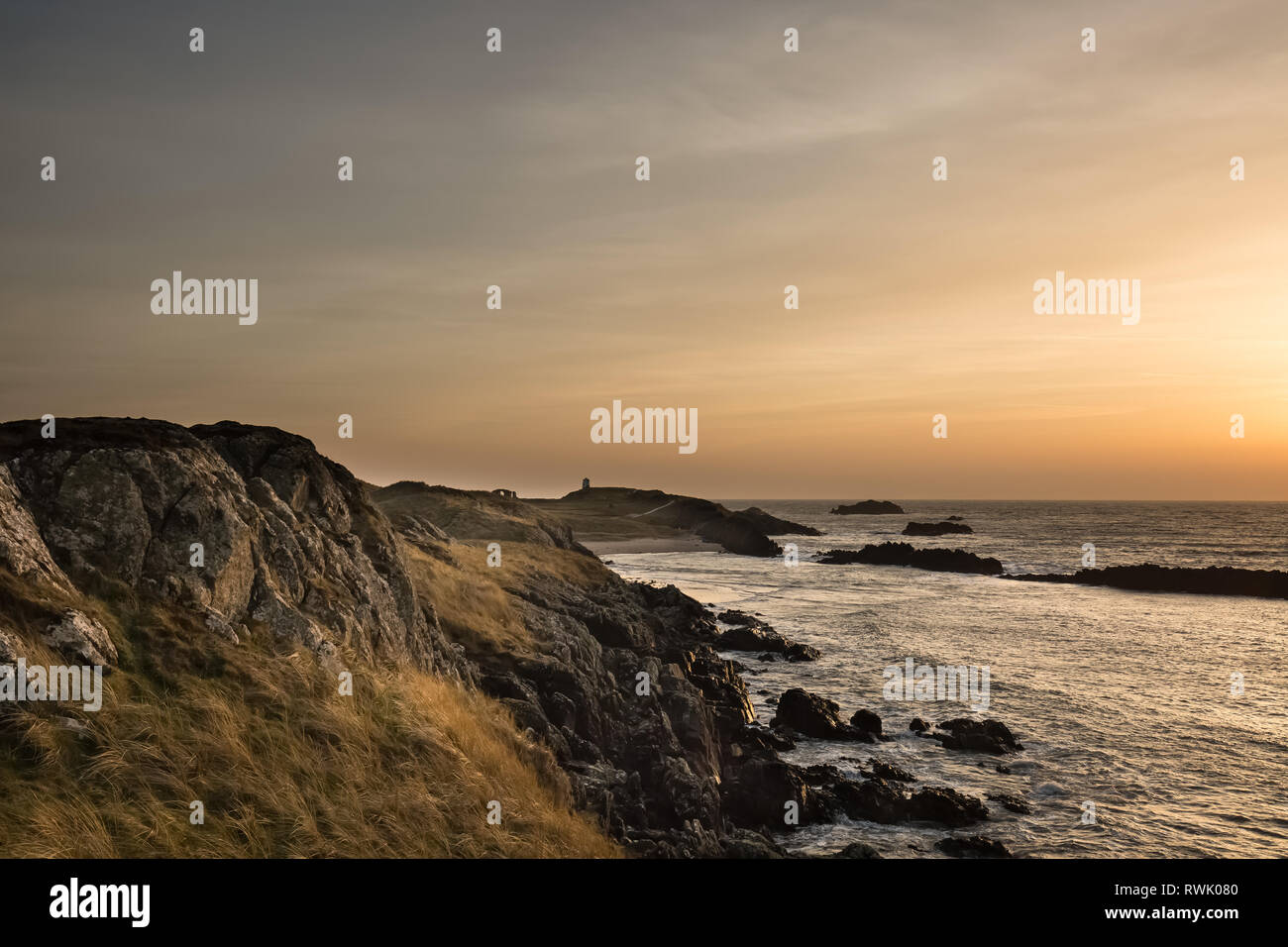An der Küste Blick auf einen Winter Sonnenuntergang, den Blick von der Halbinsel im Abend Licht, am Llanddwyn Island, Anglesey, Nordwales. Stockfoto
