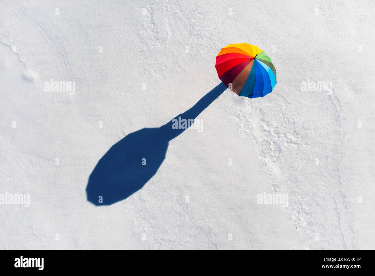 Jemand unter Regenbogenfarbenen auf weißem Schnee. Ansicht von oben Stockfoto