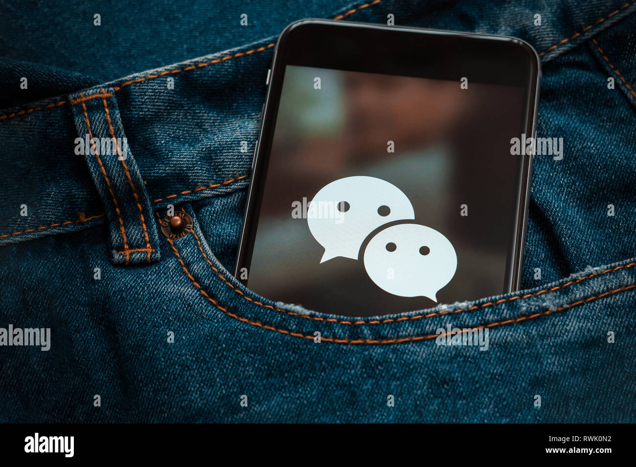Schwarz mit Logo von social media WeChat aus China auf dem Bildschirm. Social media Symbol. Denim Jeans Hintergrund Stockfoto