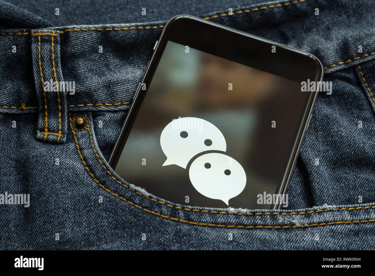 Schwarz mit Logo von social media WeChat aus China auf dem Bildschirm. Social media Symbol. Denim Jeans Hintergrund Stockfoto