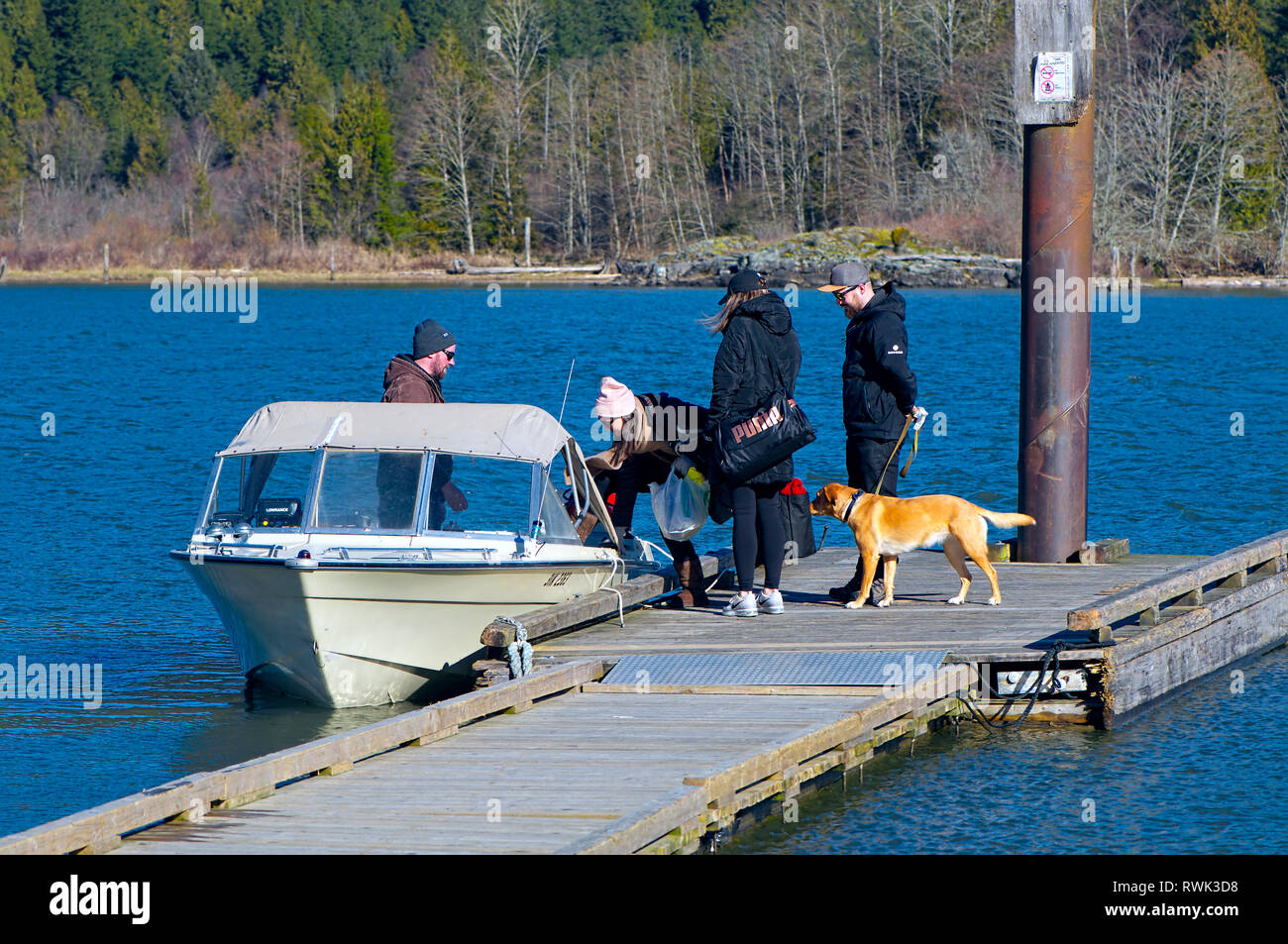 Vier junge Leute und ein Hund klettern an Bord eines angelegtes Boot in der Grant verengt Regional Park, Pitt Meadows, British Columbia, Kanada Stockfoto