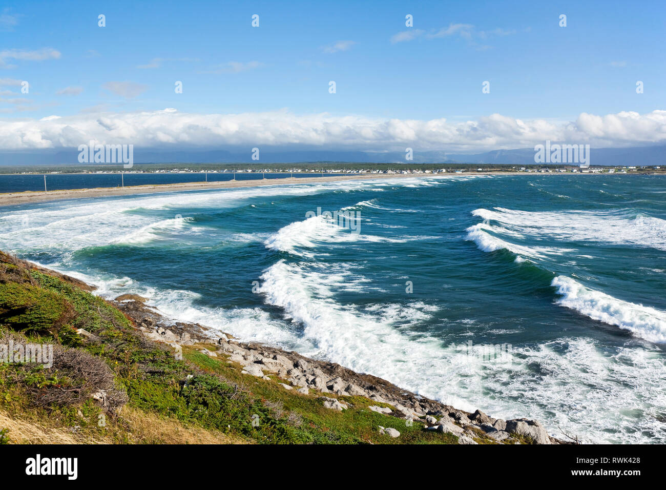 Flache Bucht in Kuh Kopf ist durch die nahezu konstante Wellen abuting 2,5 km Isthmus, der die Stadt (im Hintergrund) der Kuh Head Halbinsel (von dem das Foto aufgenommen wurde), westlichen Neufundland, Kanada gekennzeichnet Stockfoto