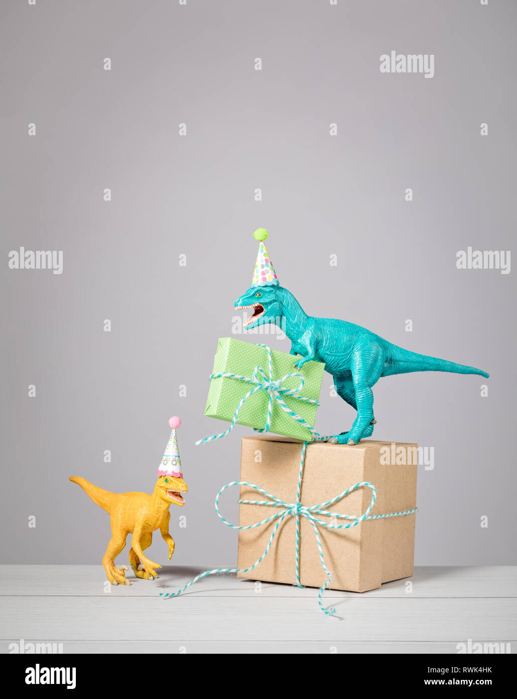 Zwei Dinosaurier mit Geburtstag Hüte und Geschenke auf einen hellgrauen Hintergrund. Stockfoto