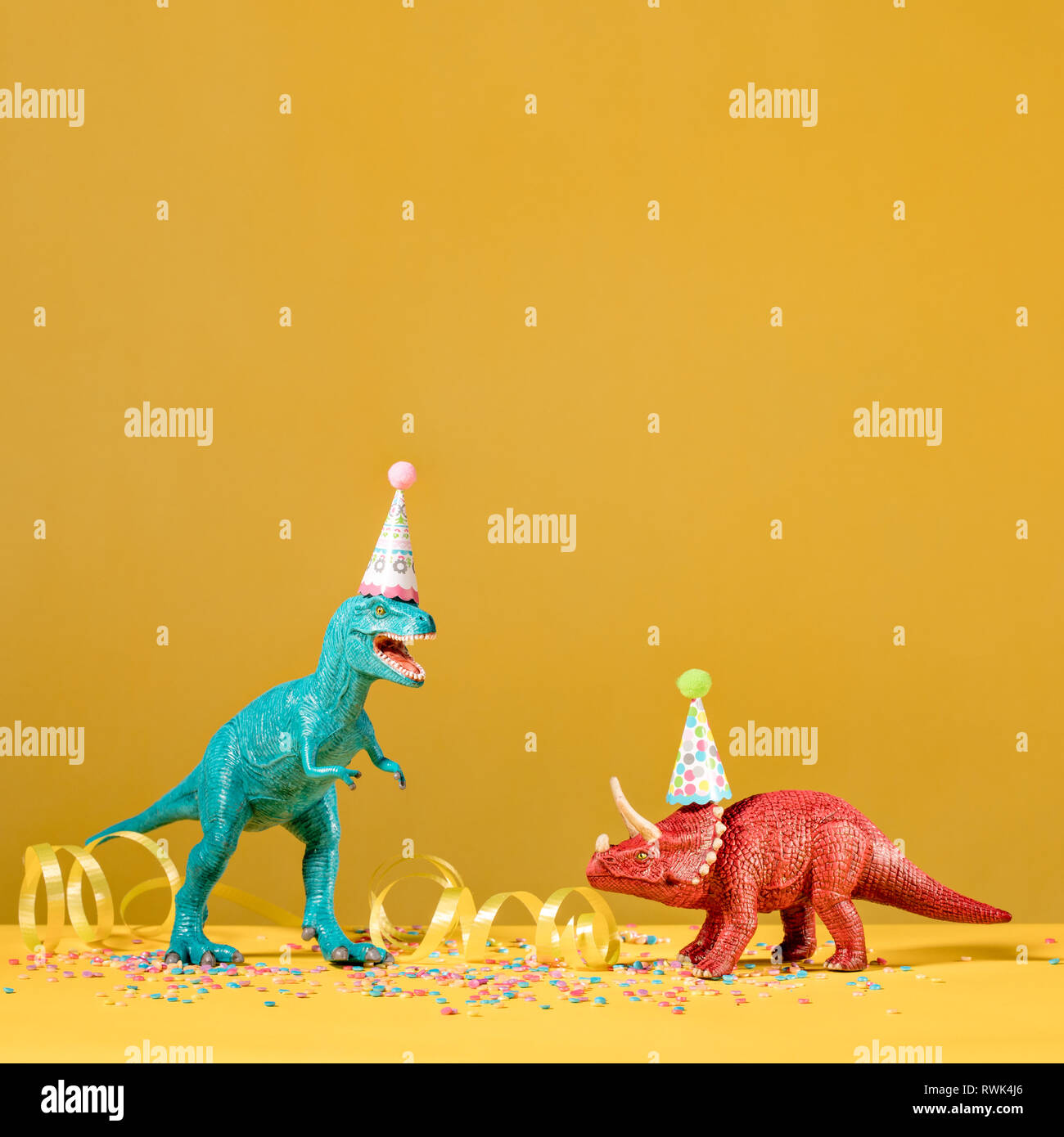 Zwei Dinosaurier mit Geburtstag hüte Feiern auf einem gelben Hintergrund. Stockfoto