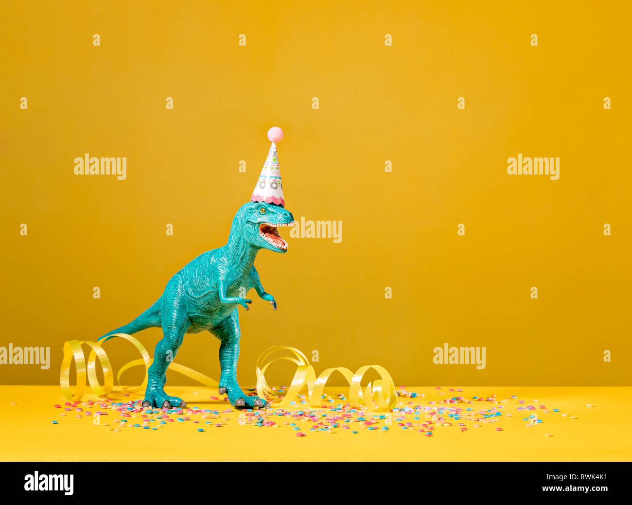 Spielzeug Dinosaurier mit Geburtstag Hut auf einem gelben Hintergrund. Stockfoto