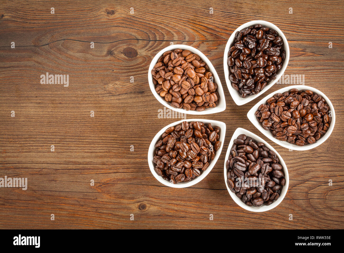 Ansicht von mehreren Sorten von frisch gerösteten Kaffeebohnen auf braunem Holz- Hintergrund mit kopieren. Stockfoto