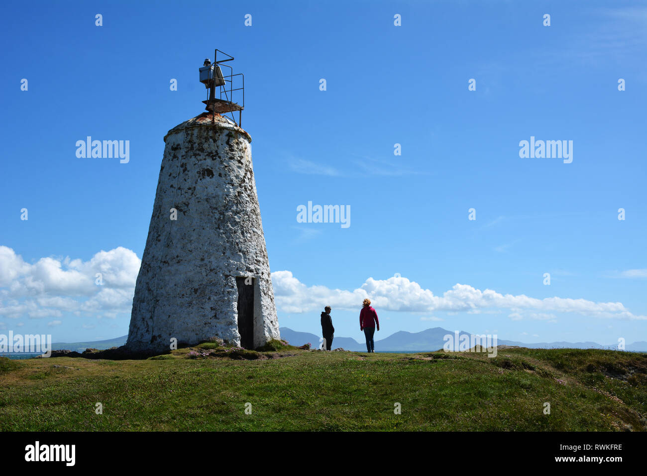 Twr Bach Rundumleuchte auf llanddwyn Island vor der Küste von Anglesey, die in den frühen 1800er Jahren gebaut wurde. Der Turm blickt auf die Berge von Snowdonia. Stockfoto