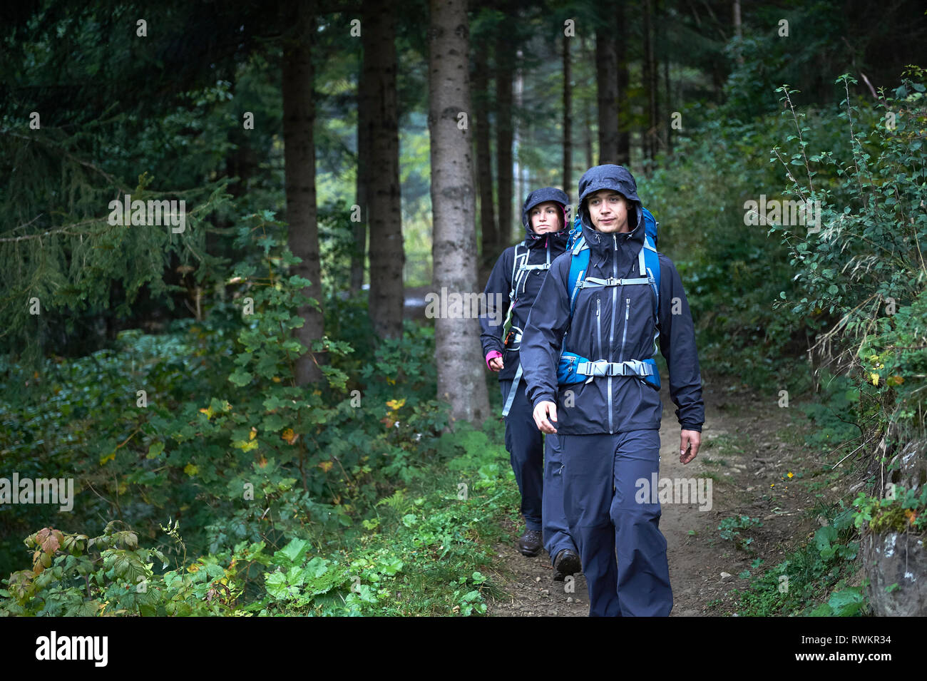 Die jungen Wandern paar Wanderungen durch Wald in hooded Anoraks, Manigod, Rhône-Alpes, Frankreich Stockfoto