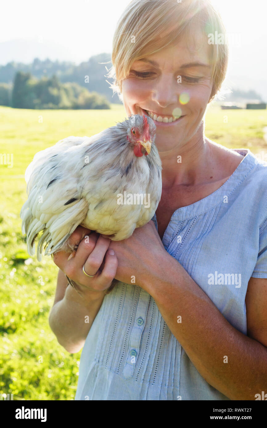 Frau, die Hahn in der Landschaft Stockfoto