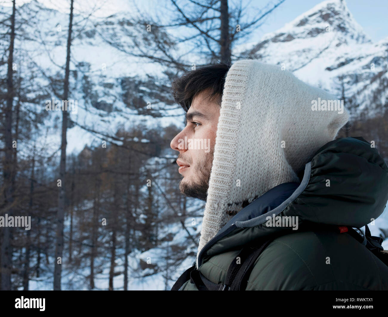 Mitte der erwachsenen Mann in Kapuzenshirt mit Schnee bedeckten Berg Wald Landschaft, Porträt, Alpe Ciamporino, Piemont, Italien Stockfoto