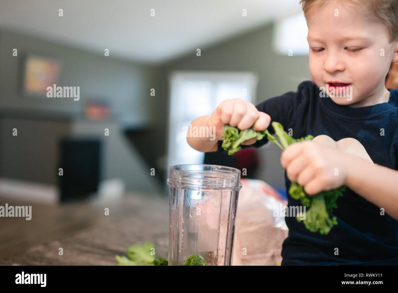 Kleinkind Schälen von Gemüse in Blender Stockfoto