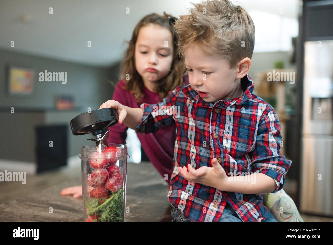 Kleines Mädchen beobachten Bruder Abdeckung blender gefüllt mit roten Rüben und Gemüse Stockfoto