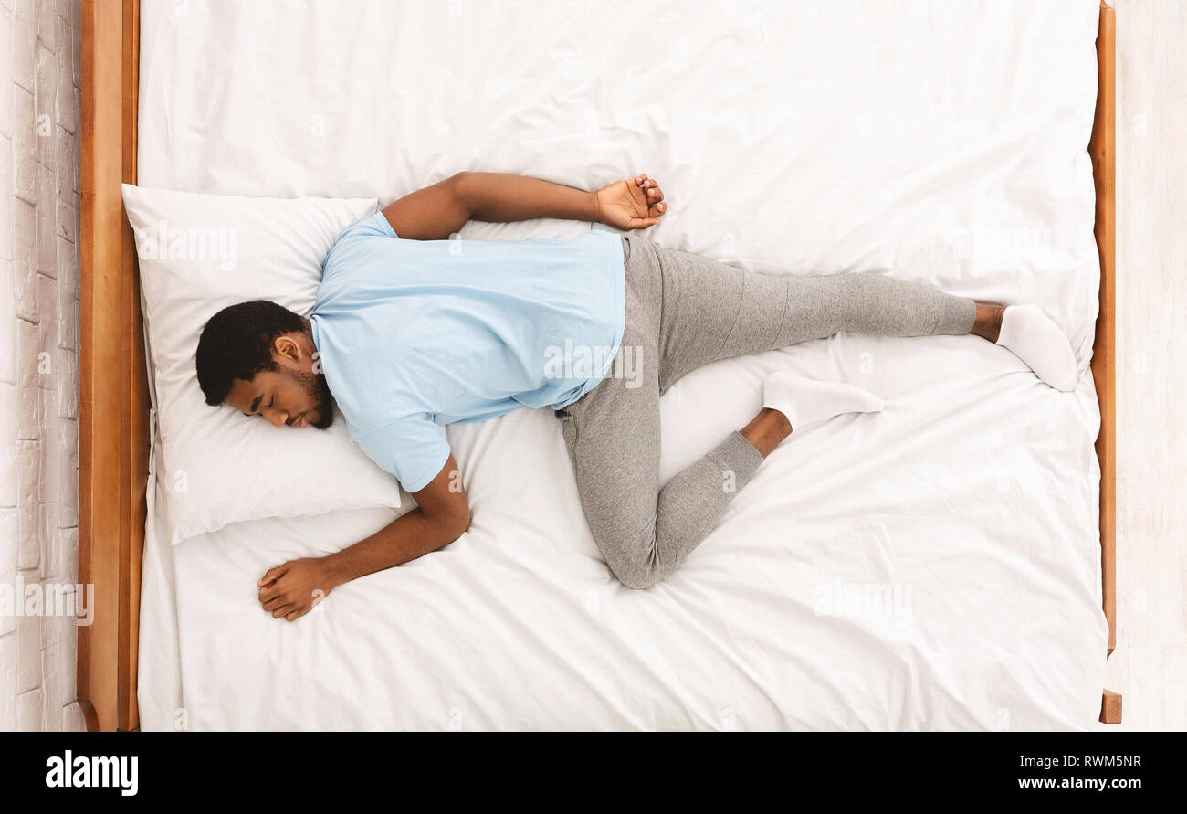 Junge afrikanische amerikanische Mann im Bett schlafen, Ansicht von oben Stockfoto