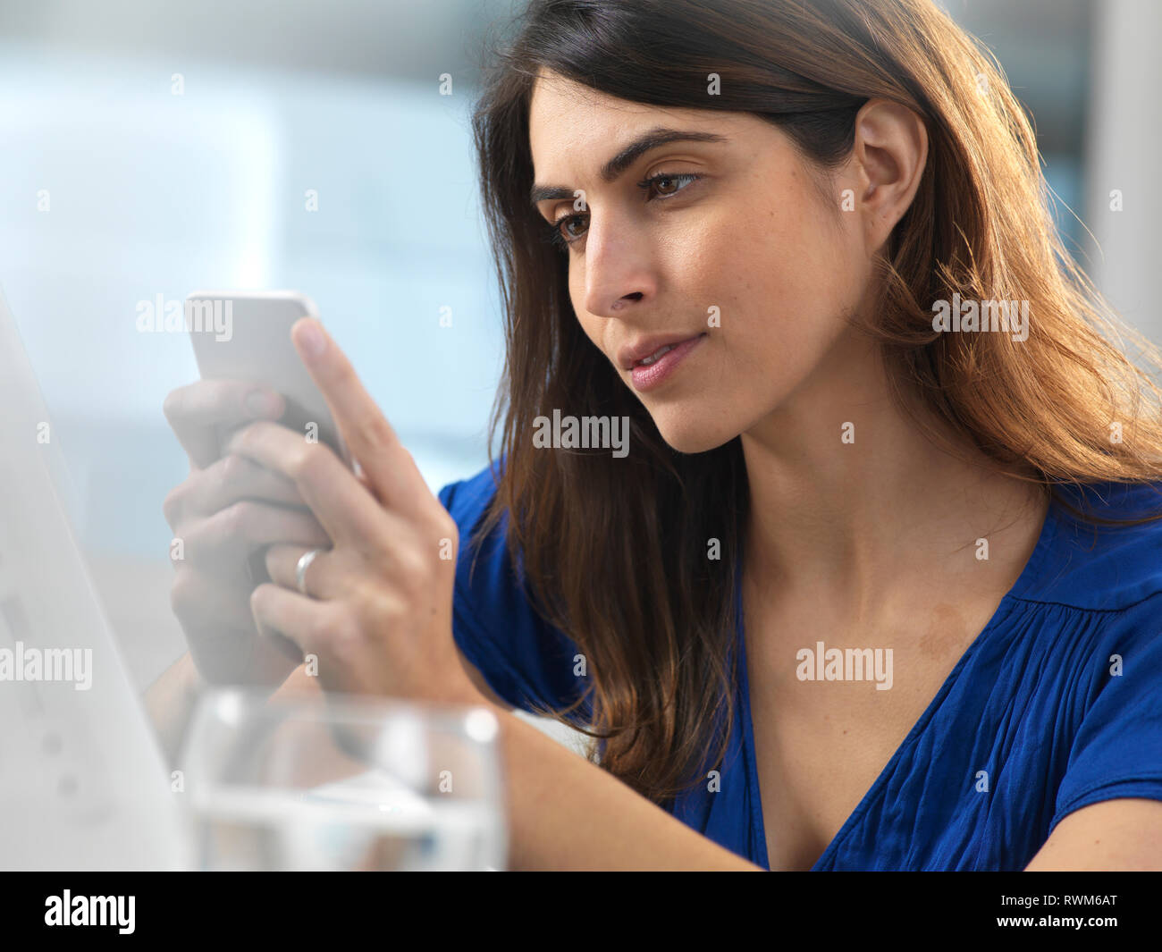 Frau mit Handy im Büro Stockfoto