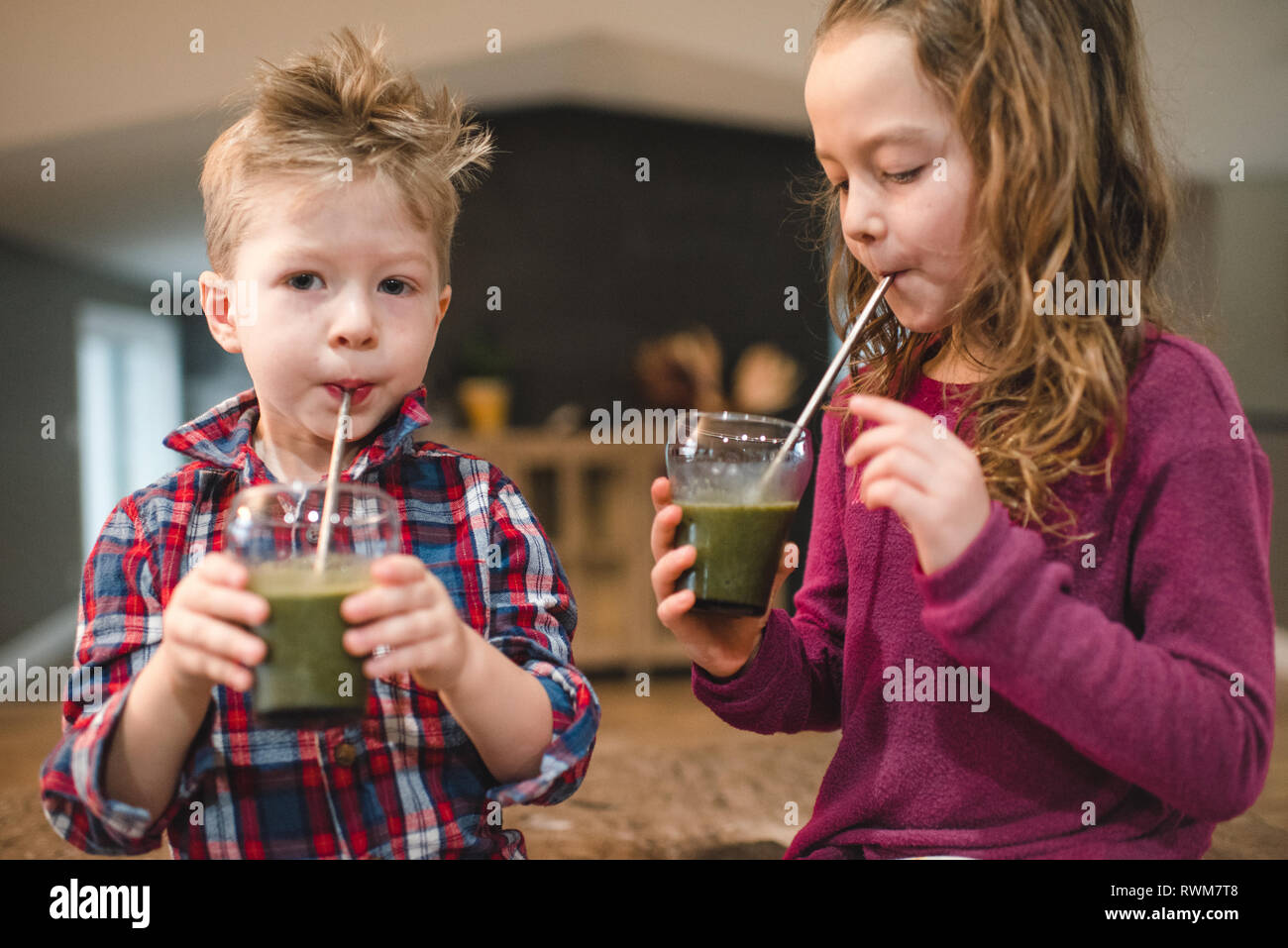 Kinder trinken grünen Saft mit Stroh Stockfoto