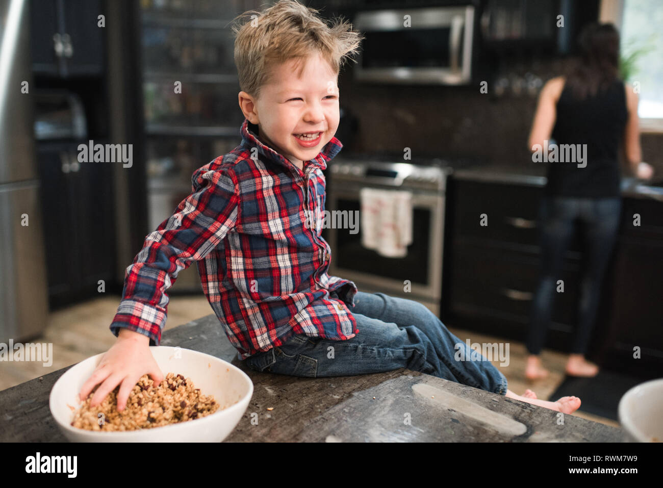 Kleinkind grabbing frisch gebackene vegetarische Saatgut Kugeln von der Schale auf der Küchenarbeitsplatte Stockfoto