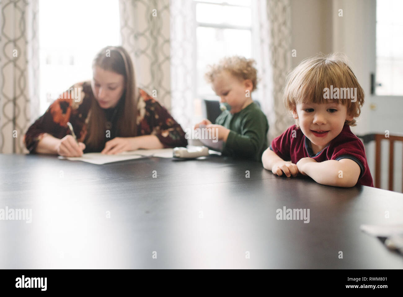 Mutter ausfüllen Formular mit Kinder spielen am Tisch Stockfoto