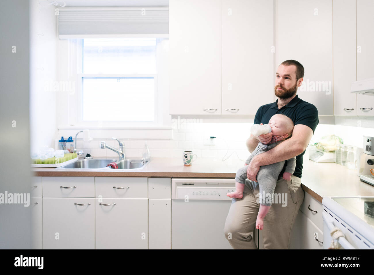 Vater das Füttern mit der Flasche baby Sohn in der Küche Stockfoto