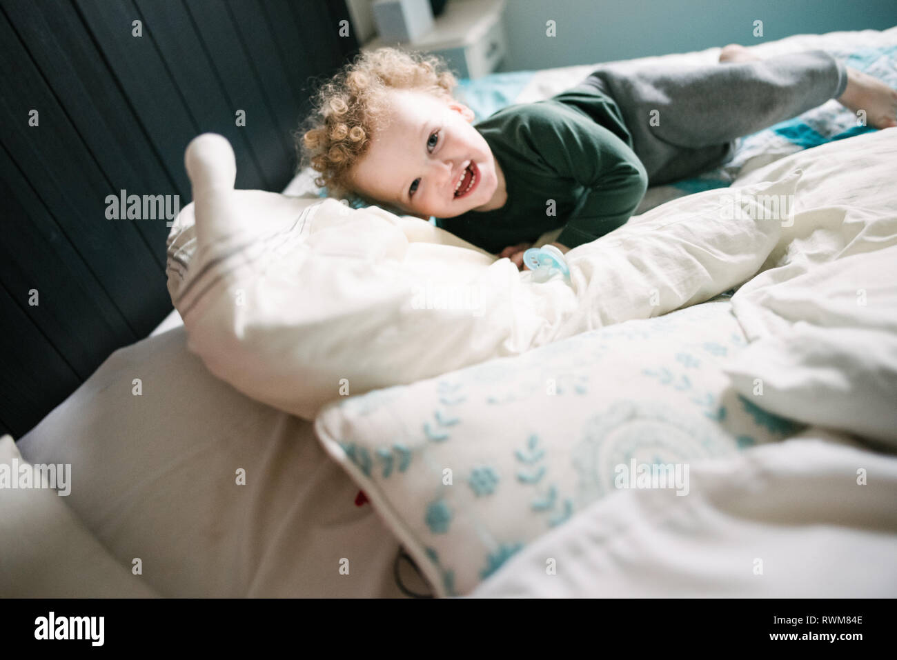 Junge lächelnd und Spielen auf dem Bett Stockfoto