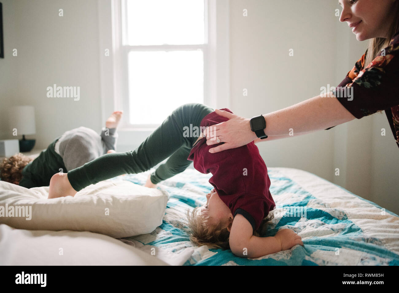 Mutter hilft Sohn Tumble im Bett Stockfoto