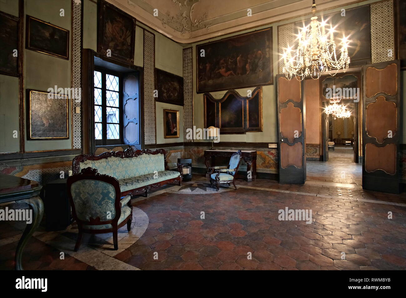 Catnia, Italien, Palazzo Biscari's Zimmer, Blick auf eine Lounge mit einem Sofa, alte Gemälde und Kronleuchter Stockfoto