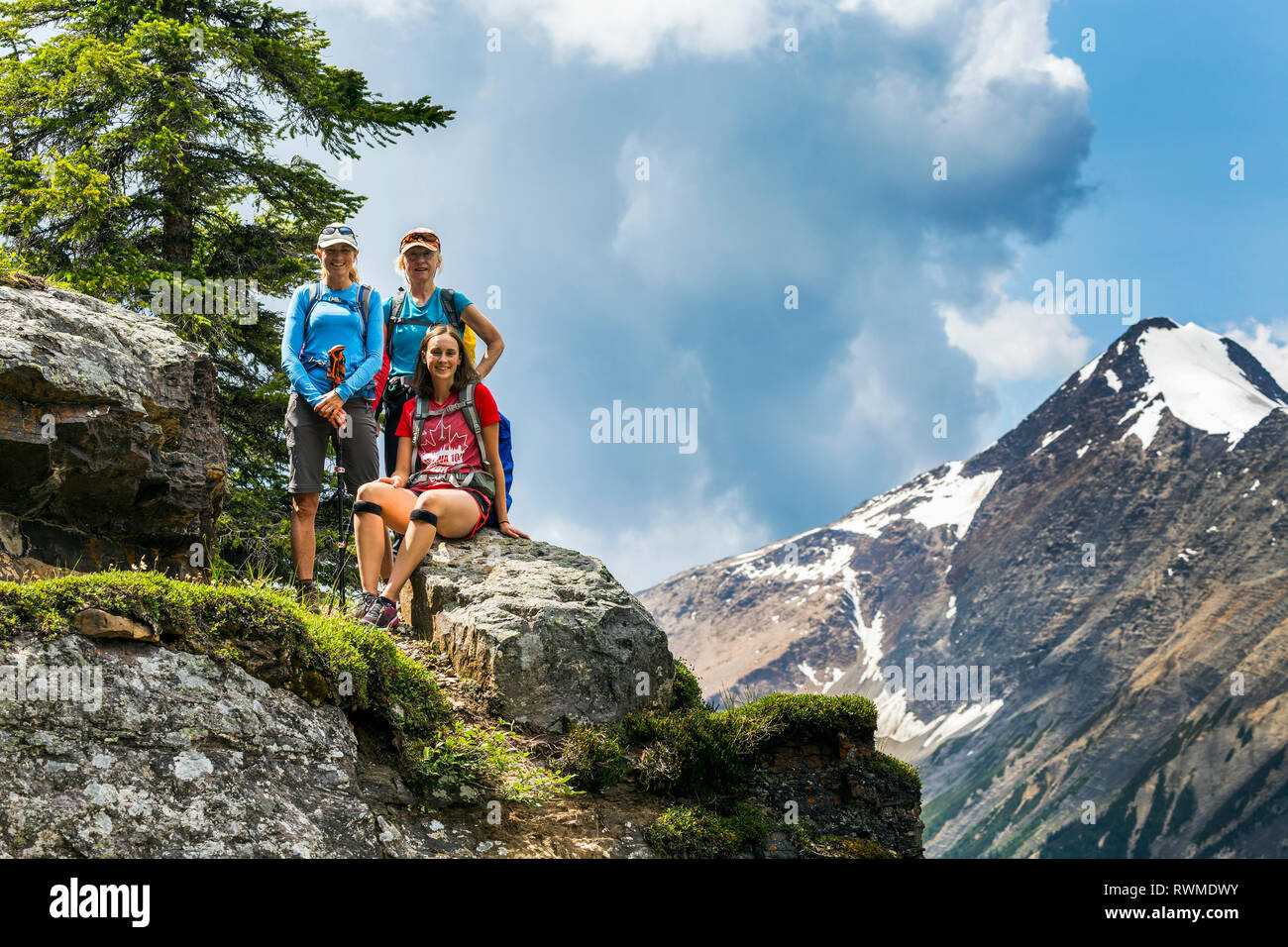 Drei weibliche Wanderer auf einem Berg rock mit Berg- und blauen Himmel im Hintergrund; British Columbia, Kanada Stockfoto