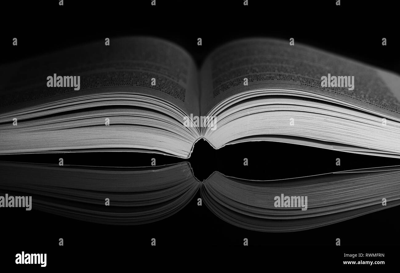 Geöffnete Buch auf schwarzen Hintergrund mit Spiegel Reflexion. Dramatische  Standlicht auf Buchen. Low-key-Fotografie Stockfotografie - Alamy
