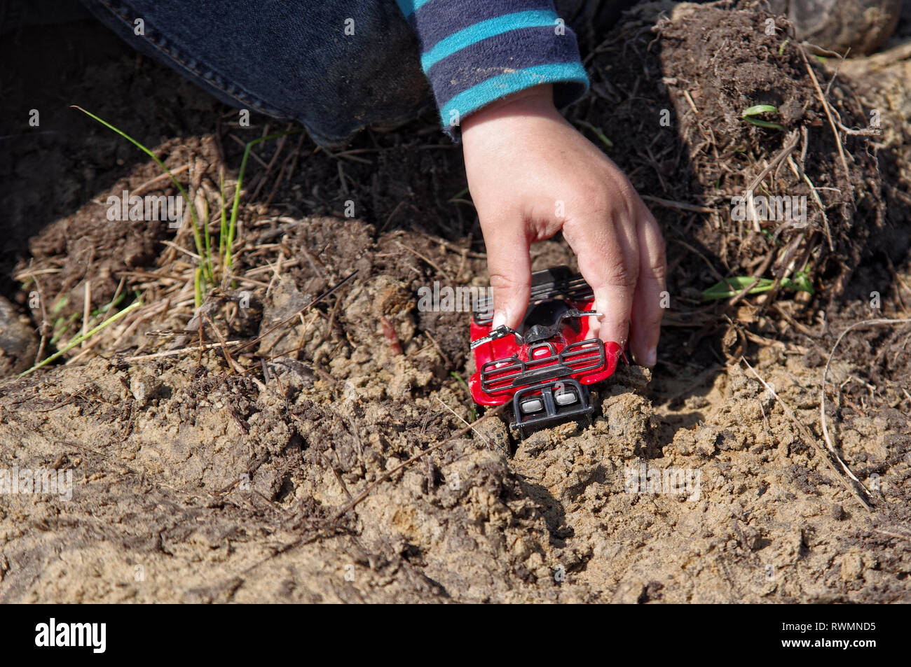 Der junge Hand spielt als Spielzeug ATV-Modell im Schlamm Stockfoto