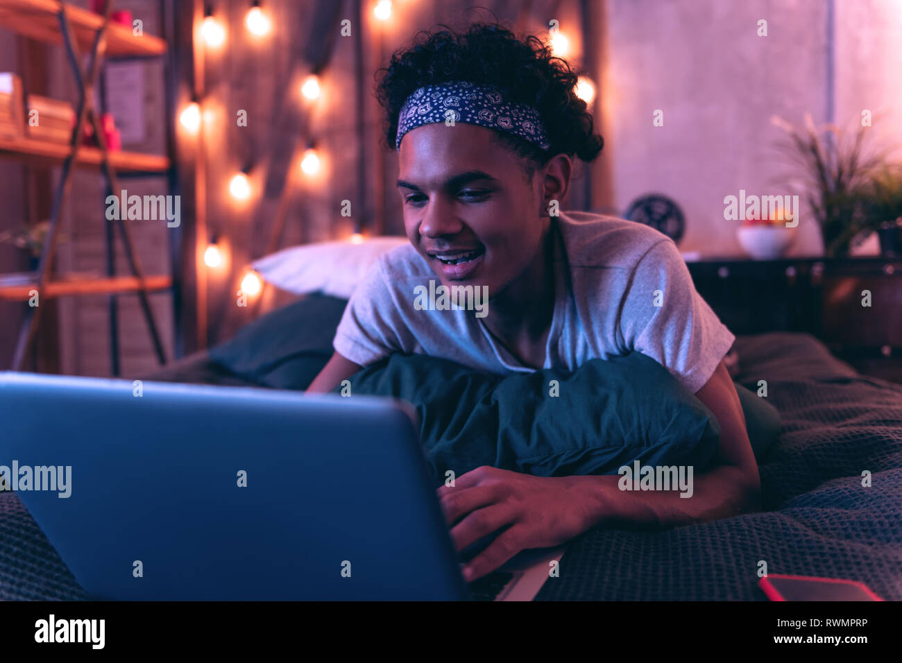 Schöne Afrikanische amerikanische Kerl spielen, computer spiel, während Sie auf dem Bett liegend Stockfoto