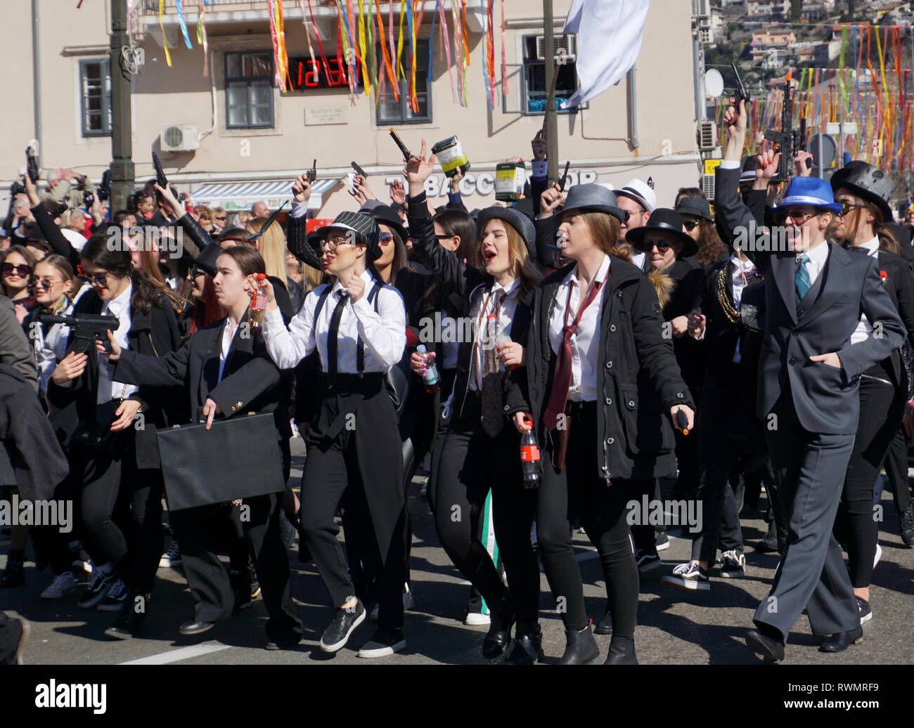 Rijeka, Kroatien, 3. März, 2019. Gruppe von Millennials in der mafia maskiert, Wandern und Singen im Karnevalsumzug Stockfoto
