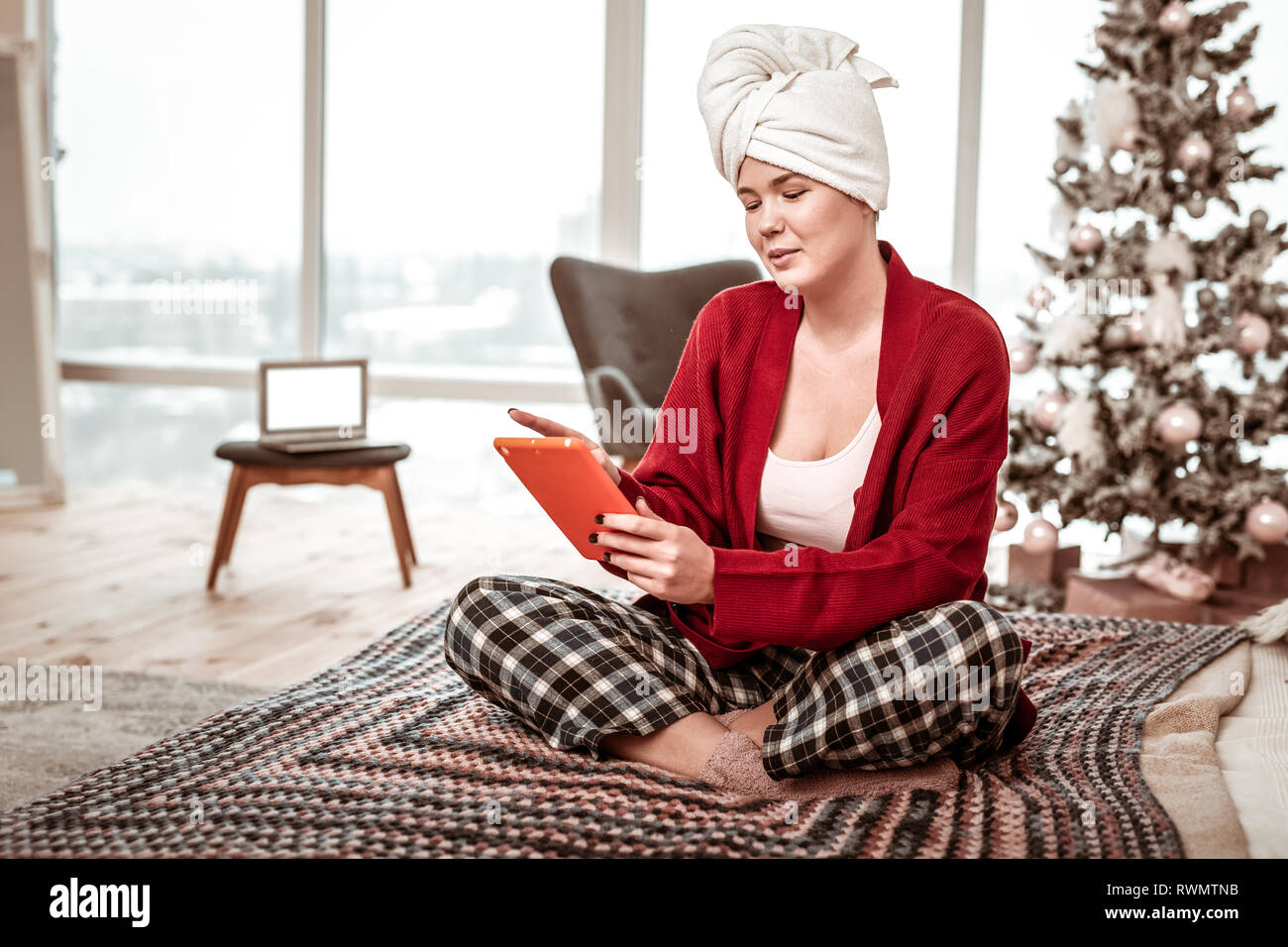 Interessierte erholsam Frau im Hause Kostüm sitzen auf dem Bett mit Tablet Stockfoto