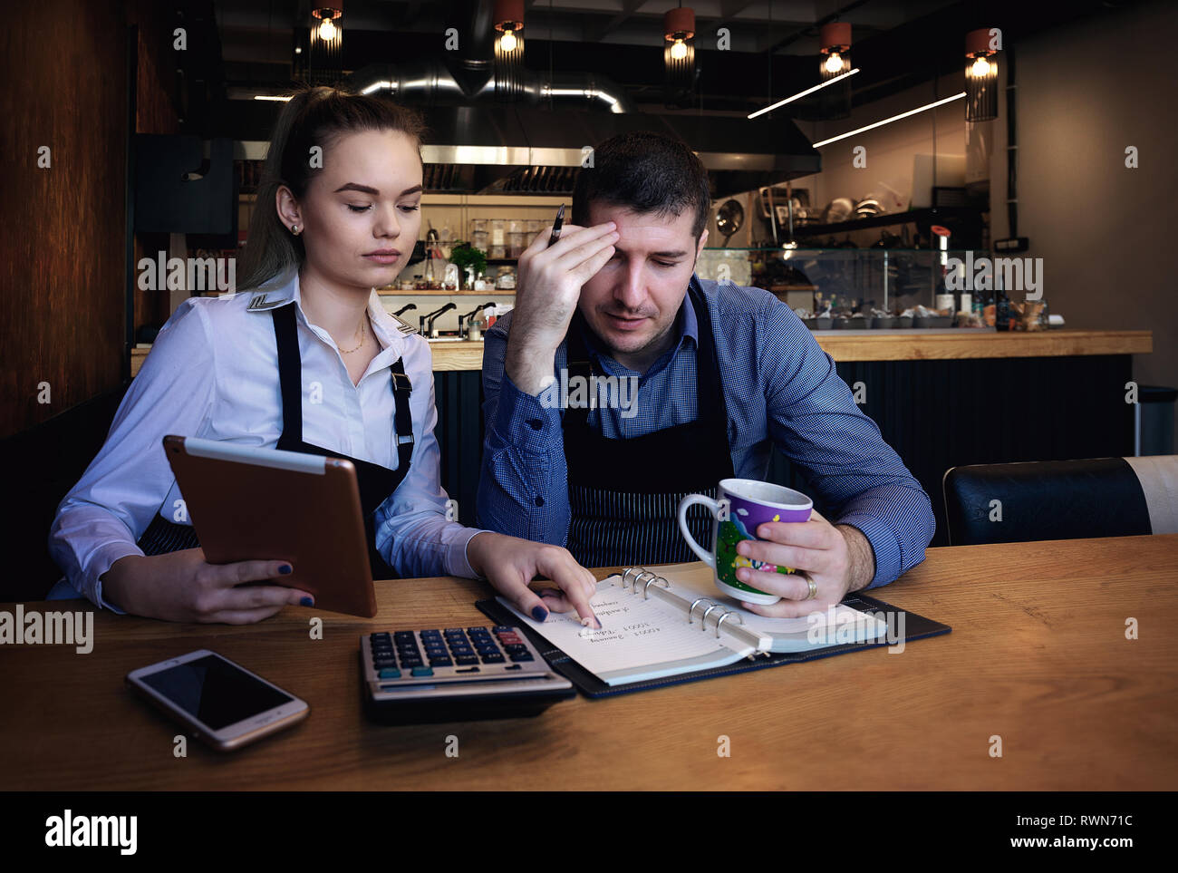 Junge Unternehmer über Dokumente im Restaurant. Auf tisch Telefon, Tablet, Tasse Kaffee, Notebook Stockfoto